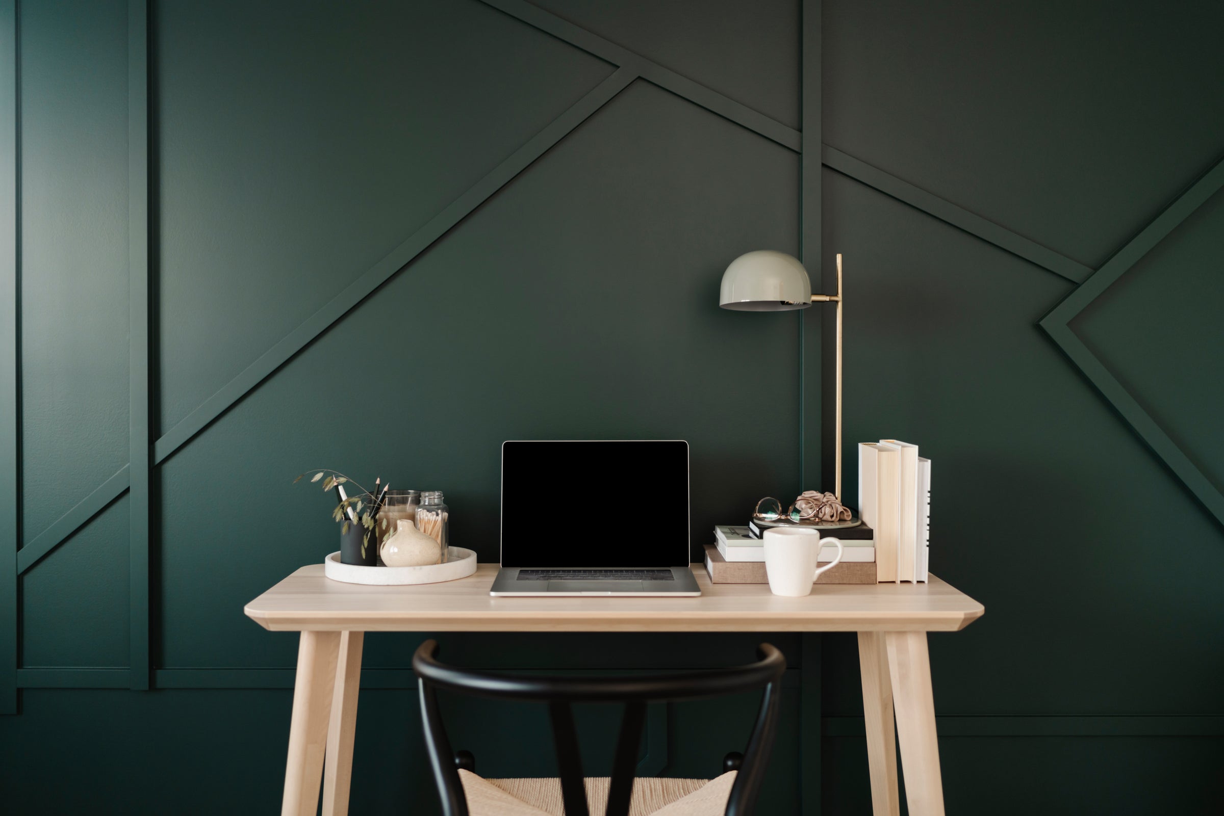 computer on desk in a very contemporary room with dark and styled wall behind