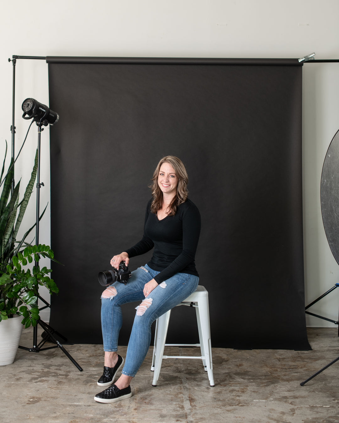 Photographer and Lawyer Rachel Brenke sitting on stool in studio with her camera