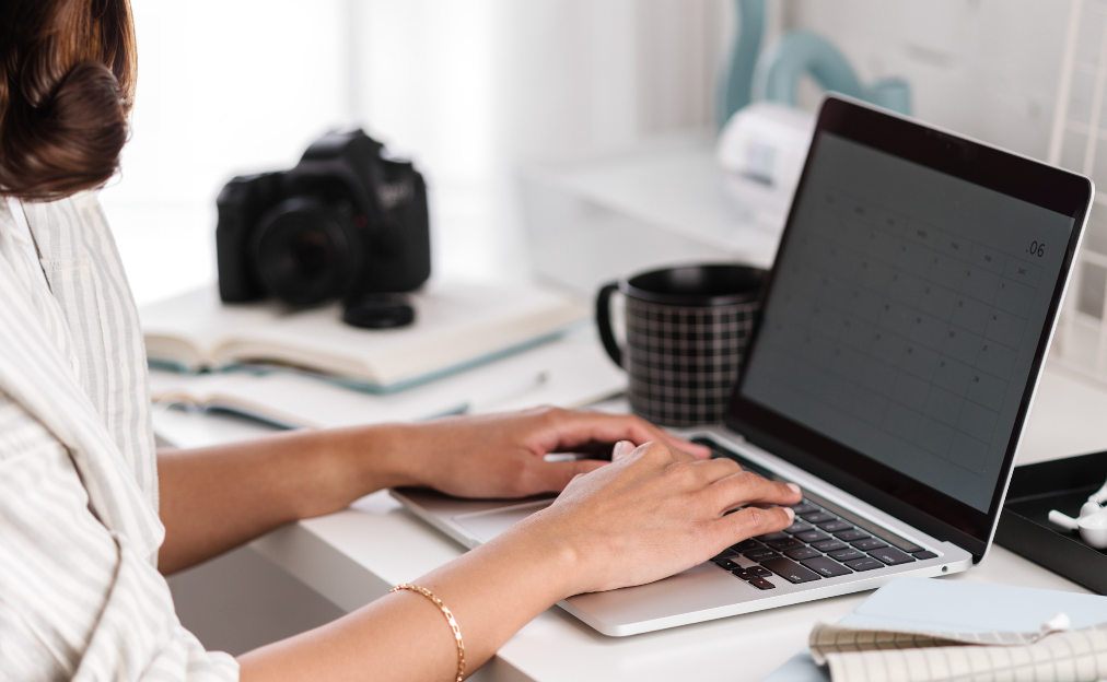 professional photographer working on laptop computer with a camera in the background