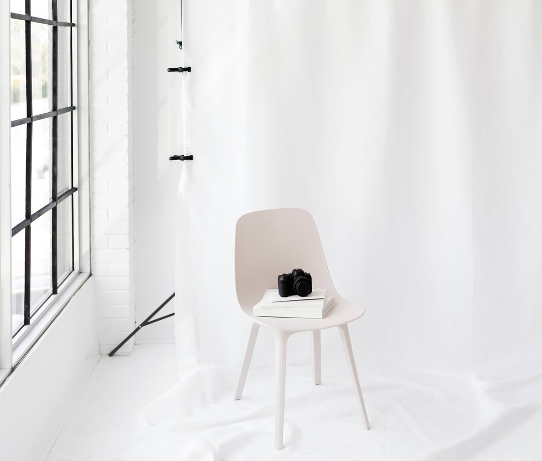 Camera sitting on chair on pile of books in an all white studio setting