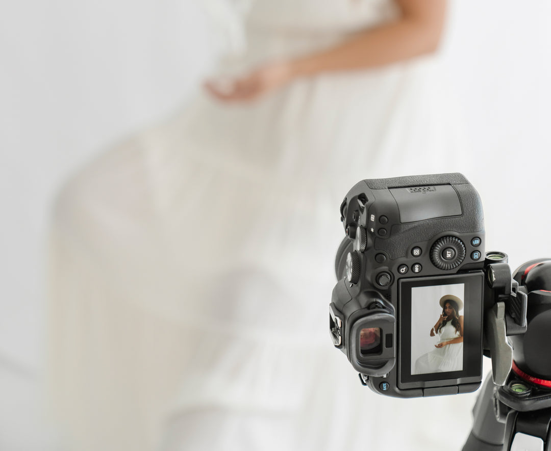 Vertical camera with view of screen showing lady in white dress with hat in a studio