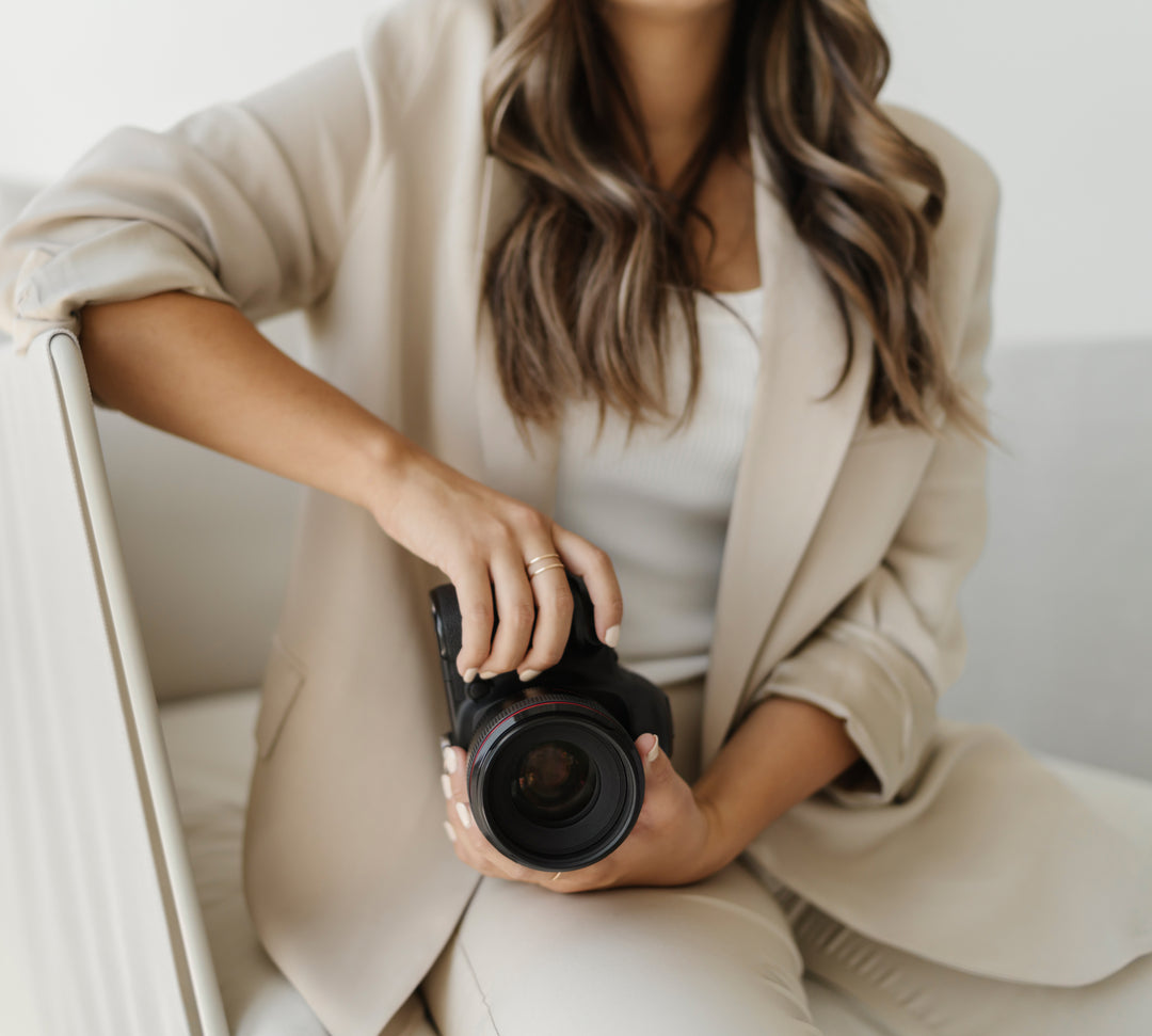 Lady in nice attire holding camera while sitting