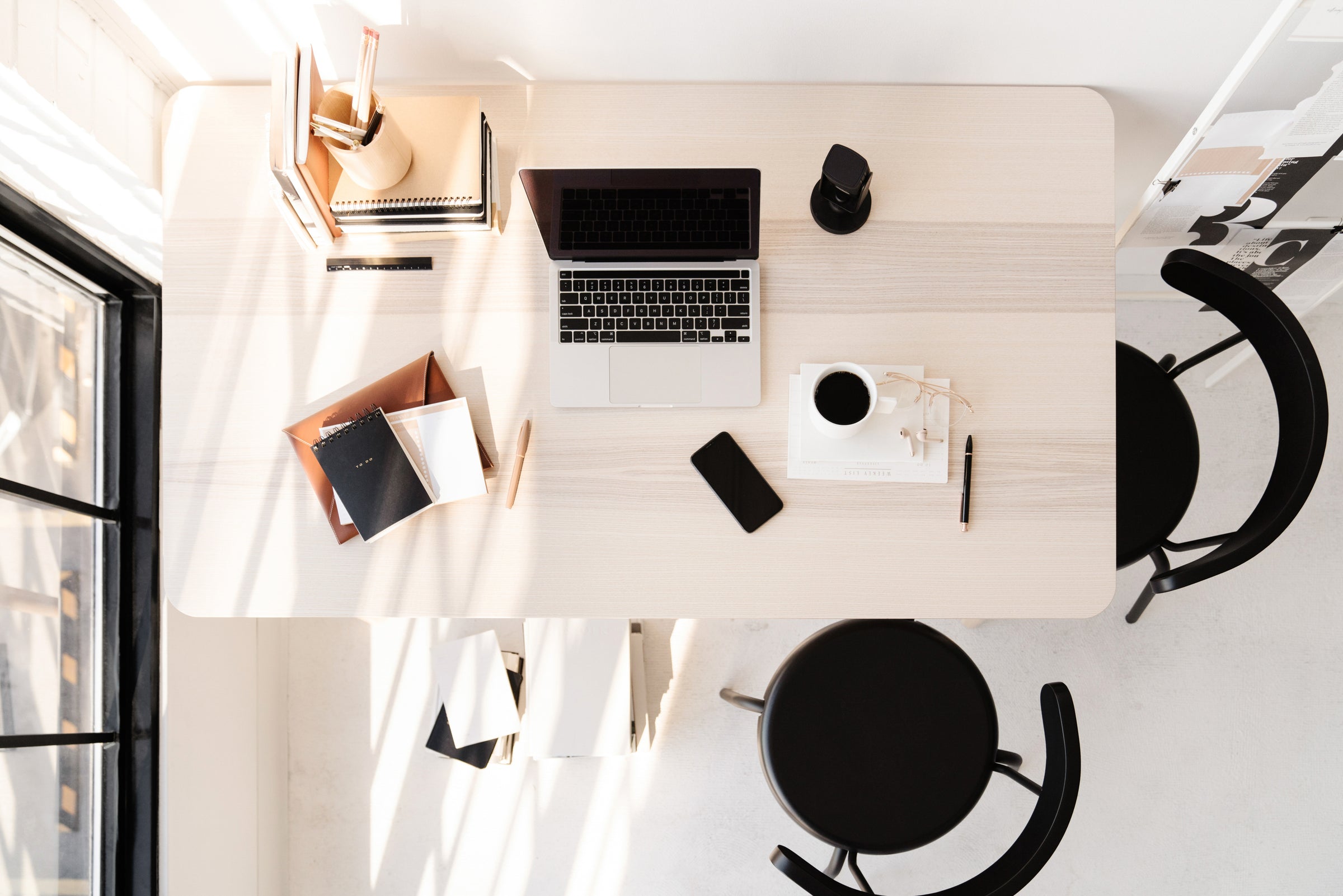 top down view of light colored wooden desk with coffee and phone