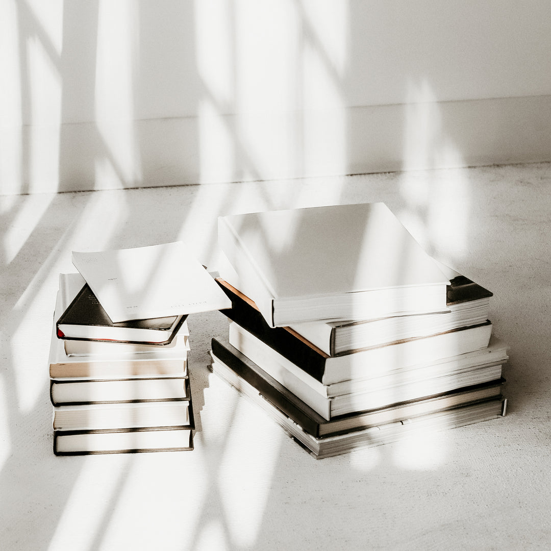 Stacks of books with no writing on them sitting on a white surface