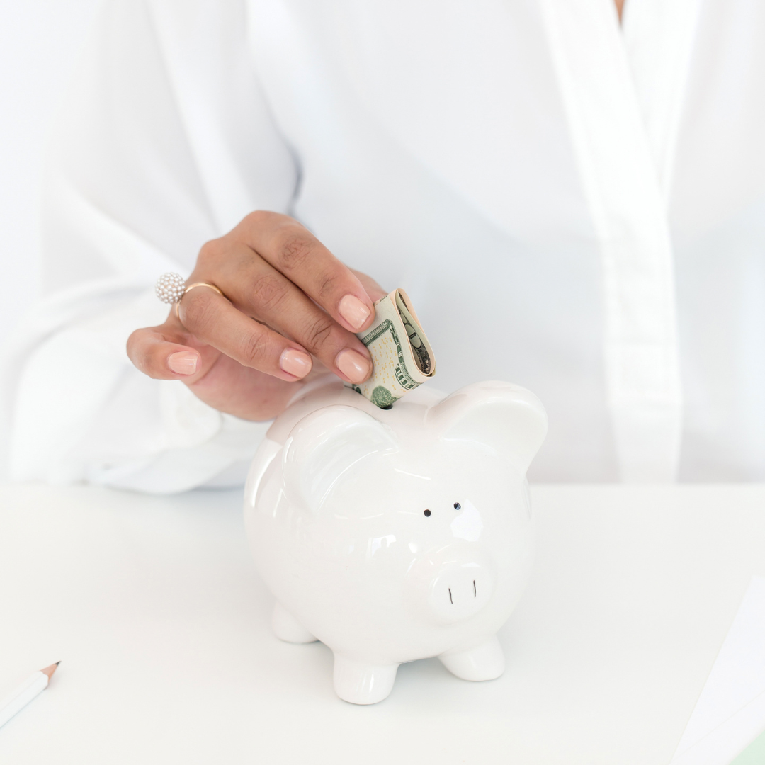 Lady placing money into a white piggy bank